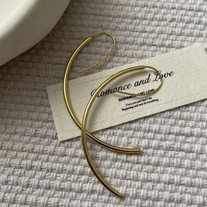 Elegant gold minimalist wavy hoop earrings on a textured white background with decor