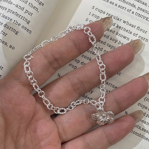 Macro detail of 925 sterling silver floral charm bracelet with vintage hollow flower design