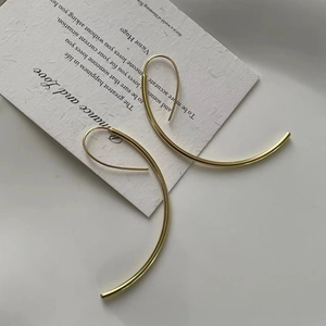 Detail of large gold C-shaped minimalist earrings on elegant white literary card