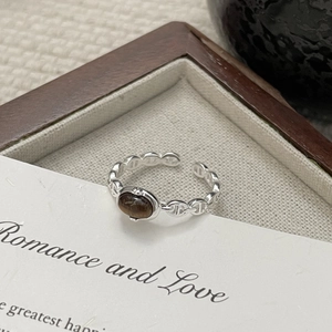 Macro shot of silver pig nose ring featuring an oval brown tiger eye stone setting