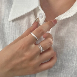 Detail of silver S925 minimalist stacked rings and twisted band on a hand