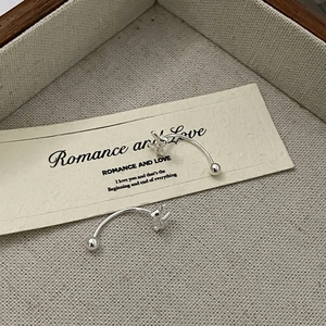 Detail of S925 sterling silver bow earrings featuring a polished bead on beige fabric