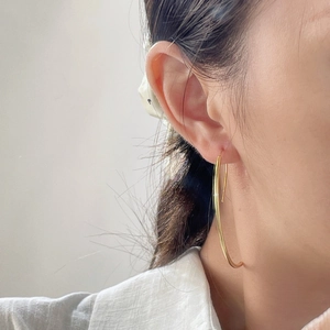 Close-up of elegant large gold curved earrings worn by a model in a minimalist style