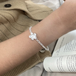 Close-up of handmade 925 sterling silver floral bracelet worn with vintage brown knitwear