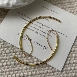 Detail of minimalist wavy gold drop earrings on elegant background with poetic text