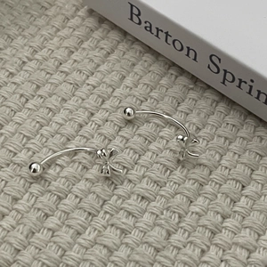 Detailed close-up of S925 sterling silver bowknot C-shaped earrings on knit fabric