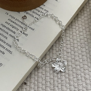 Handcrafted 925 sterling silver flower bracelet with heart tag on aesthetic book background