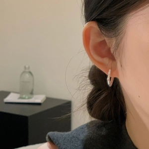 Detail of silver geometric rectangular earrings worn by a model in a minimalist style