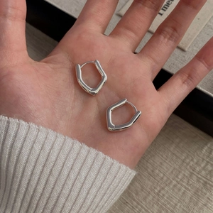 Close-up of polished S925 sterling silver irregular U-shaped hoop earrings in hand