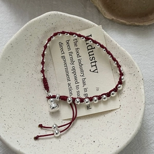 Macro view of adjustable red braided rope bracelet with S925 sterling silver beads and bell