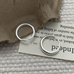 Detailed view of polished S925 sterling silver open rings on a textured background