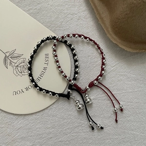 Detailed macro view of S925 sterling silver hulu charms on woven red and black rope bracelets