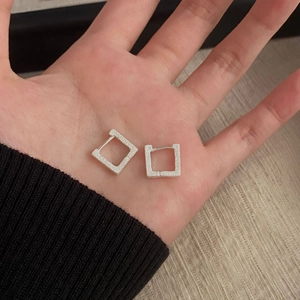 Dettaglio macro di orecchini geometrici quadrati in argento con finitura opaca sabbiata