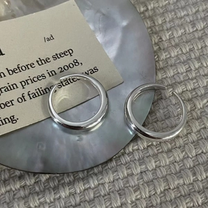 Close-up of polished S925 sterling silver adjustable rings on gray tray