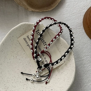 Detail of S925 sterling silver gourd pendant on red and black hand-woven rope bracelets