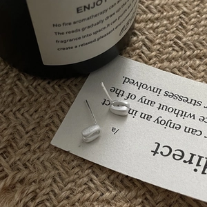 Macro shot of minimalist silver stud earrings with a textured matte finish on card