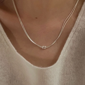 Detail of S925 sterling silver double snake chain necklace with a stylish knot pendant