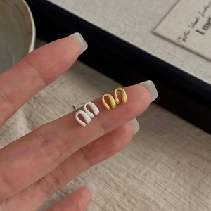 Detailed close-up of minimalist U-shaped matte silver and gold studs held by hand