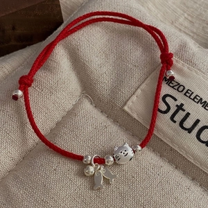 Close-up of S925 sterling silver cat and fish charms on a hand-woven red string bracelet