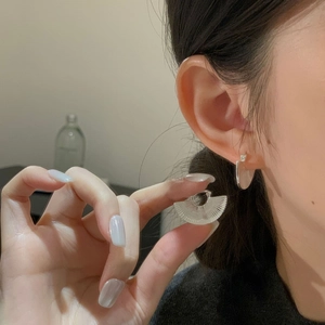 Macro shot of fan-shaped transparent acrylic earrings with elegant vertical textures