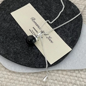 Detail view of S925 silver necklace featuring a black round pendant on a neutral felt base