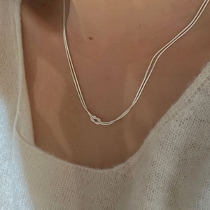 Close-up of elegant S925 sterling silver double-layer knotted snake chain necklace on neck