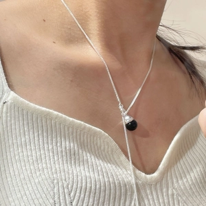 Detail of S925 sterling silver Y-necklace with black crystal bead on white sweater