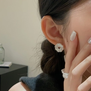 Close-up of minimalist silver multi-line geometric earrings and ring on a female model