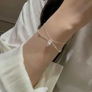 Detail shot of a layered silver heart bracelet featuring round beads and a sleek O-chain
