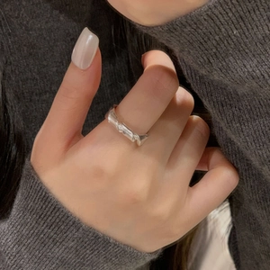Detail shot of a matte S925 sterling silver knotted ring on a grey knit sleeve background
