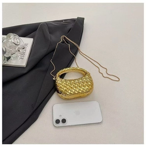Vue de dessus d'un mini sac à main tissé doré avec chaîne posé sur une veste grise