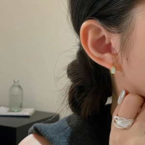 Detail showing shell inlay gold hoop earrings and layered silver ring on a model