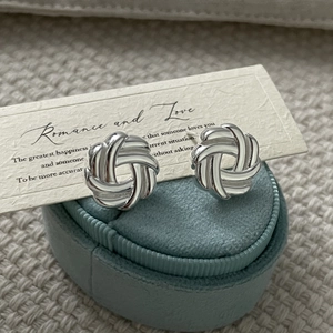 Detail of 925 sterling silver twisted knot earrings on a velvet jewelry box display