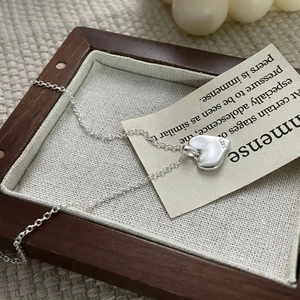 Detailed view of S925 sterling silver heart pendant with retro matte finish on wood
