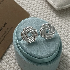 Detailed close-up of 925 sterling silver woven knot earrings on a blue velvet jewelry box