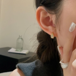 Close-up of elegant gold shell earrings and layered silver ring worn by a woman