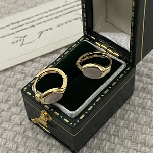 Detail view of gold earrings with oval shells in a dark green velvet jewelry gift box