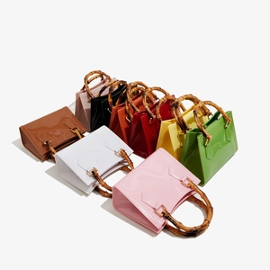 Detail view of colorful glossy PVC handbags with bamboo handles and metallic gold buckles