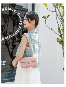 Detail shot of a pink quilted chain crossbody bag featuring a golden interlocking buckle