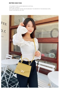 Detail view of bright yellow PU crossbody bag with elegant gold W buckle on a white outfit