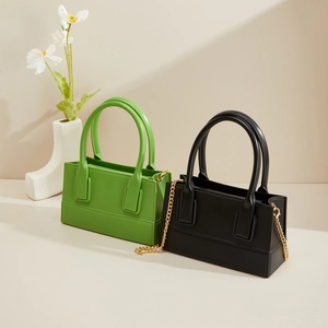 Detail of square PVC jelly bags in black and green with gold metal chain straps