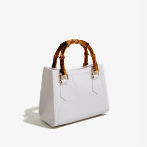 Detail of white glossy PVC bag with natural bamboo handle and golden hardware connectors