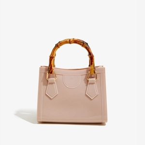Close-up of pink PVC square jelly bag featuring classic bamboo handle and gold hardware