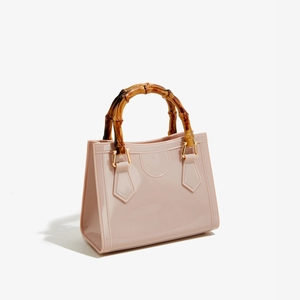 Detailed close-up of pink PVC jelly bag with bamboo handle and golden hardware