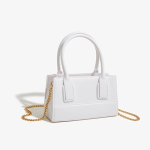 Detailed view of the white PVC jelly bag featuring a golden chain strap and top handles