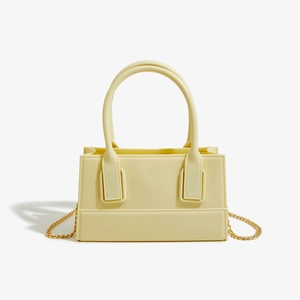 Close-up of yellow PVC jelly handbag featuring gold chain strap and smooth texture