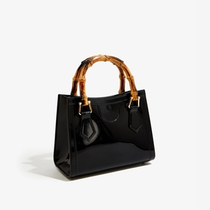 Detail view of the retro bamboo handle and glossy black patent leather finish on the handbag