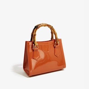 Detailed close-up of the orange jelly bag featuring vintage bamboo handles and gold hardware