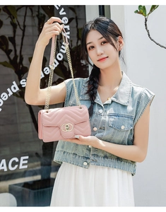Close-up of pink quilted chain bag with elegant gold interlocking clasp and leather strap