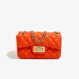 Detail of orange quilted crossbody bag with golden chain strap and metallic twist lock